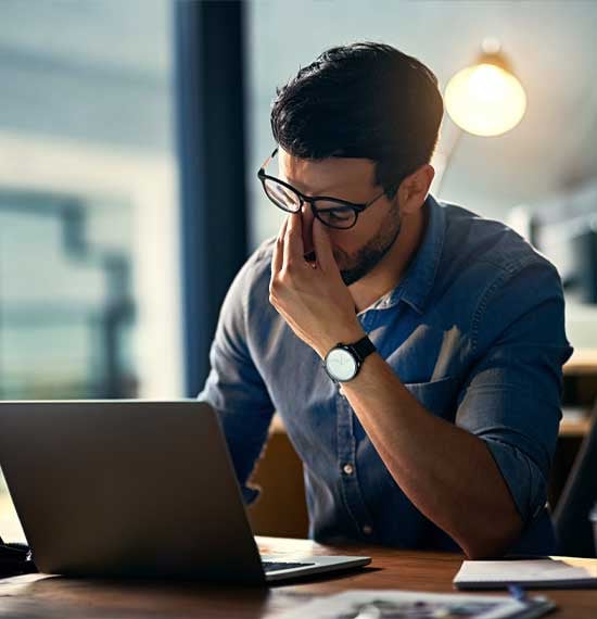 Frustrated worker at a laptop overwhelmed by the consequences of inferior IT and cybersecurity threats