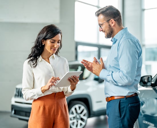 An image with a female and man having a conversation representing how One Step Secure IT experts are ready to assist car dealer owners with their security.