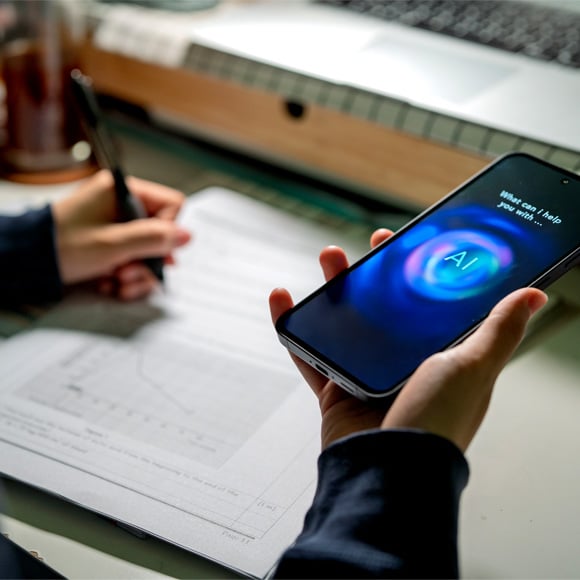 Image of a person on their work desk using AI on their mobile phone.