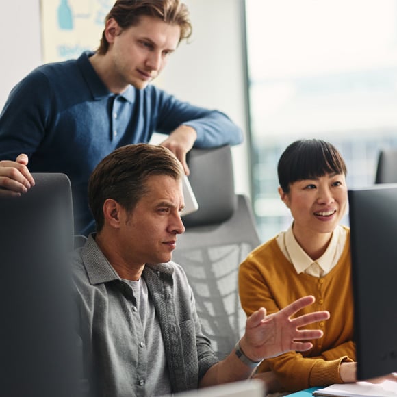 Employees and business owner looking at a computer as they review Hatz AI.