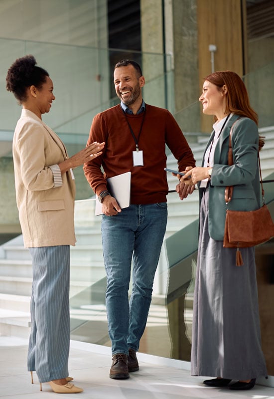Image of two executive women conversing happily with a male IT expert about cybersecurity.