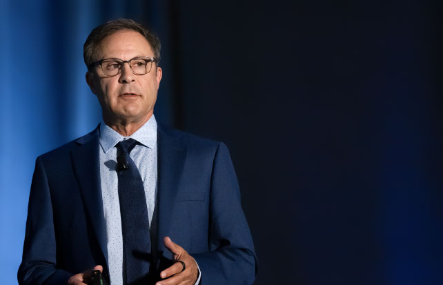 Image of Scott Kreisberg speaking on stage with a blue background.