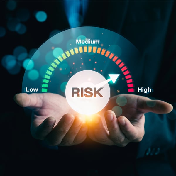 Blue background image displaying a low to high risk meter on someone's hands representing the high stakes of cyber crime. 